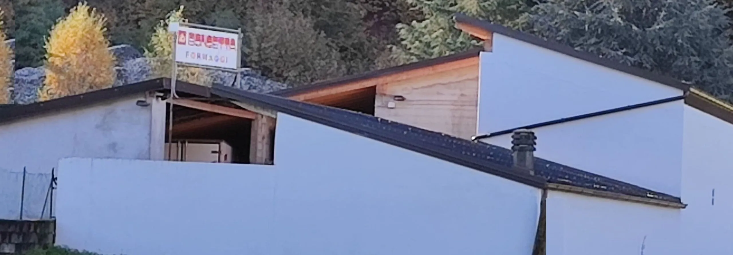 La sede della Bongetta Formaggi a Cosio Valtellino: edifici bassi con l’insegna dell’azienda, bosco alle spalle.
