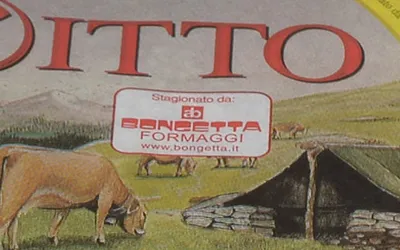 Dettaglio dell’etichetta del Consorzio sulla forma di Bitto DOP: un riquadro bianco con la scritta «Stagionato da:», il monogramma «ab» e «Bongetta Formaggi — www.bongetta.it».